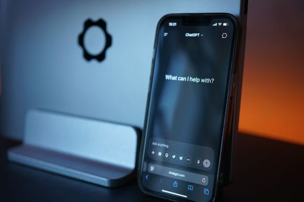 Smartphone screen showing ChatGPT with the text: "What can I help with?" on a dark background