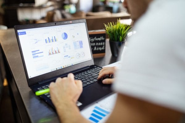 marketing-attribution-without-guesswork-a-practical-guide-for-small-teams | DOWO Digital Person typing on a laptop showing colorful data dashboards and charts in a cafe setting
